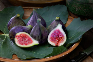 Ripe figs with leaves in terracotta bowl Ripe figs with leaves in terracotta bowl